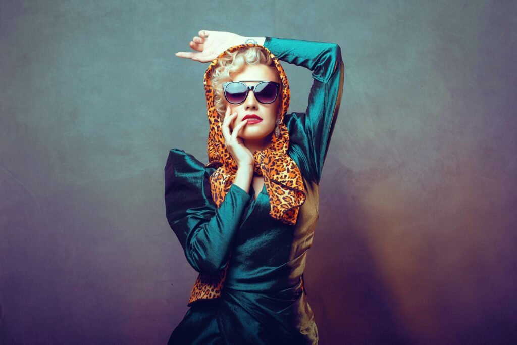 Elegant portrait of a woman in vintage attire with sunglasses and headscarf. Studio shot.